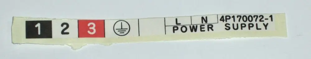 Hinweisschild von Daikin für einen Power Supply mit Angaben zu Stromverbindungen (L, N) und Erdungssymbol. Enthält Beschriftungen in Schwarz und Rot.